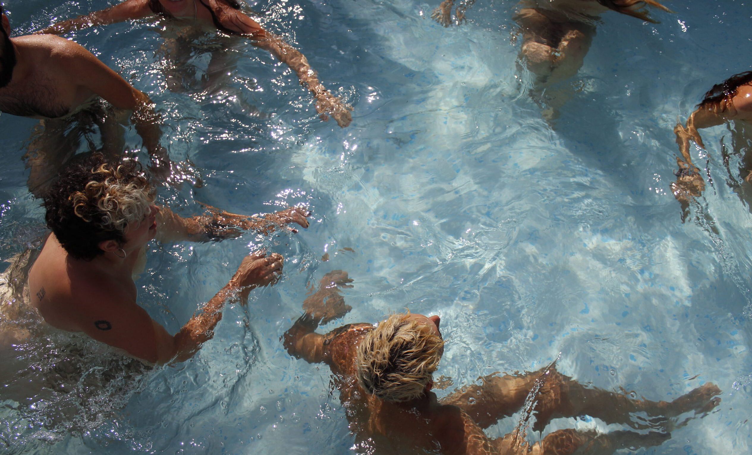 Spiegelung der Sonne und nackte Körperteile im Wasser aus dem Pool.
