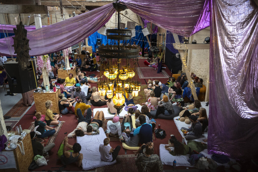 Die Scheune von oben nach unten fotografiert, es sind viele Menschen in einem Kreis zu sehen