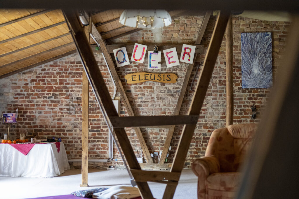 Auf dem Bild ist an der Wand der Schriftzug: Queer - Eleusis zu sehen, das ist ein Workshophraum